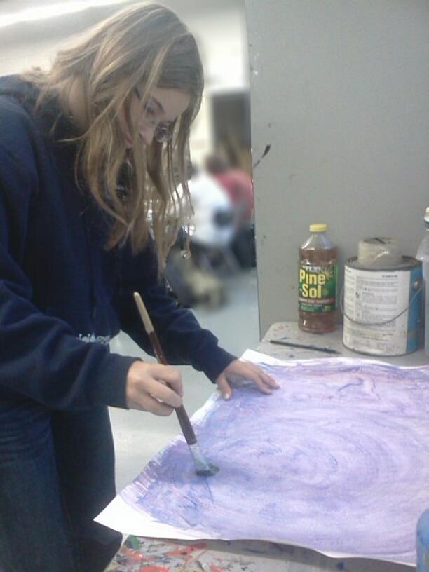 Junior, Natalie Petrucka, working on her mavelous art work creating a background for her portriat using water color paint.